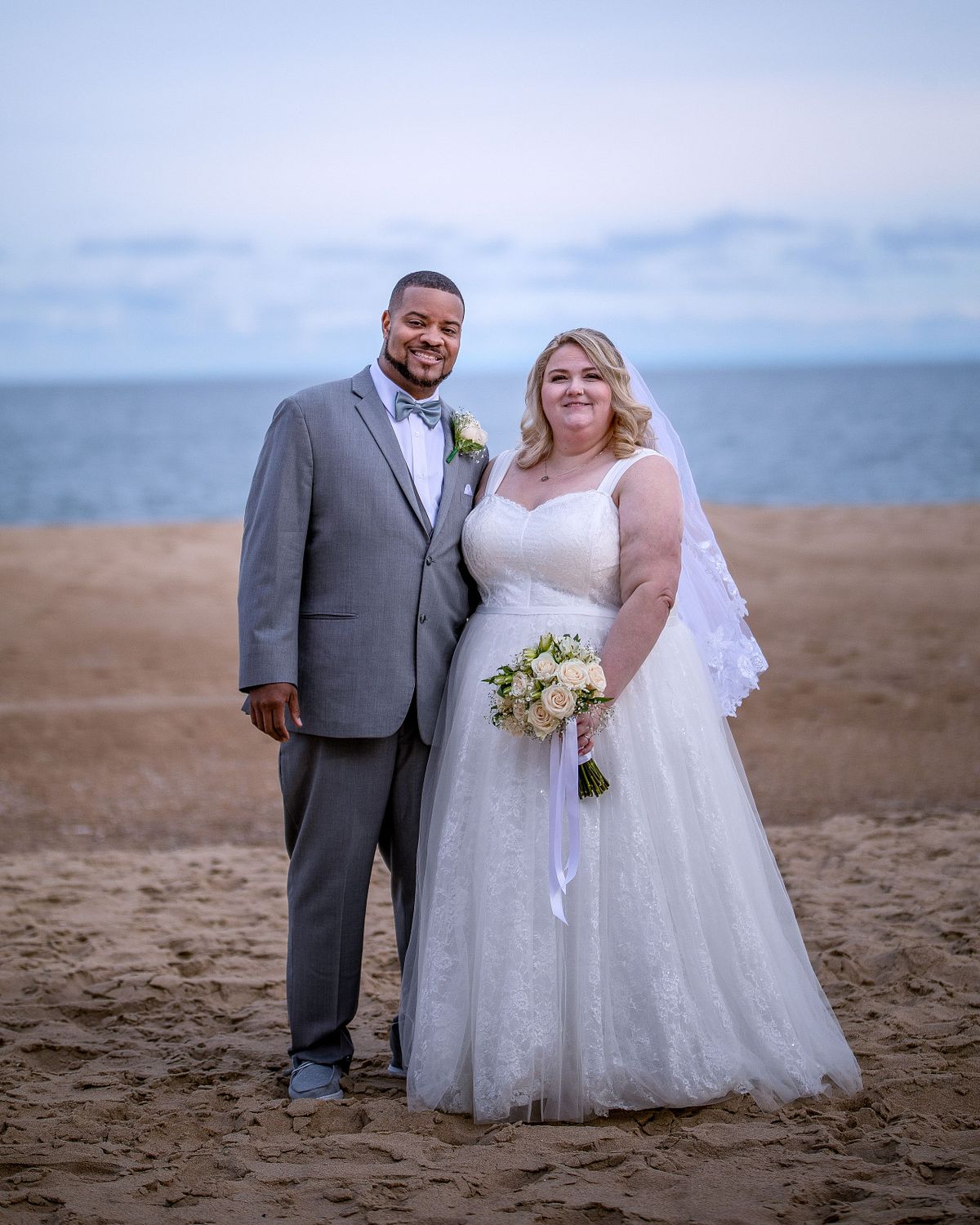 bride and groom posing on a empty beach after tourist season in late october during sunset hours
