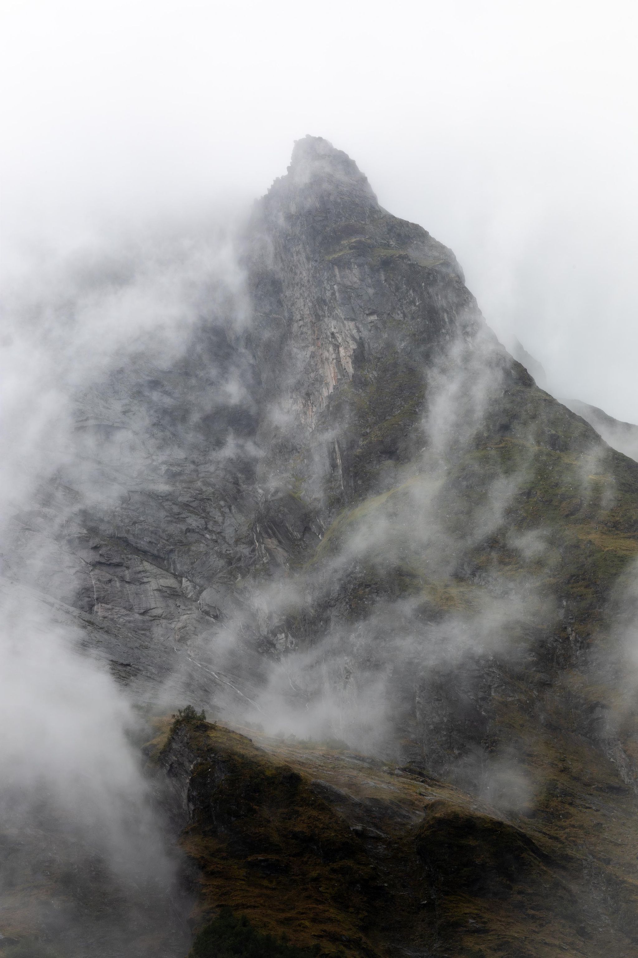 Montagne rocheuse en Norvège enveloppée de brume et de nuages, photographie de paysage nordique