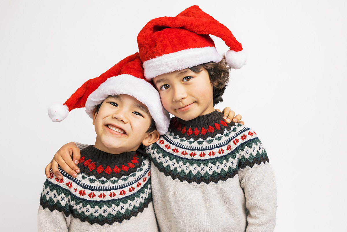Two smiling brothers with arms around each other wearing matching Nordic sweaters during a holiday mini session.