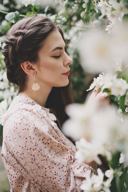 Dreamy spring photooshoot of a model surrounded by blossoming tres