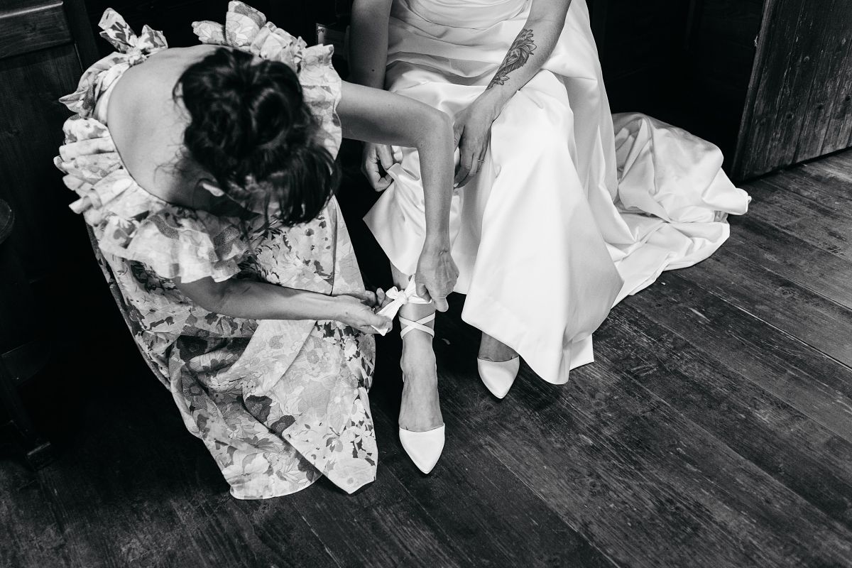mother in law placing wedding shoe on bride in Kalamata Greece &ndash; traditional wedding preparation
