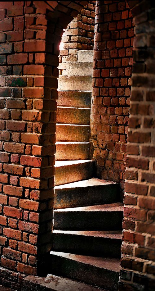 Elegant curved staircase amidst red brick walls.