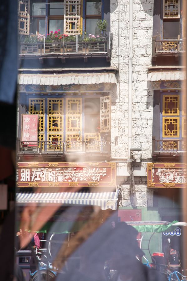 Female store manican reflected in window in Tibet with Tibetan building in the background
