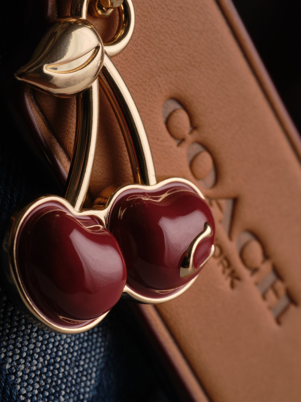 Close detail of a luxury purse hanging cherries charm.