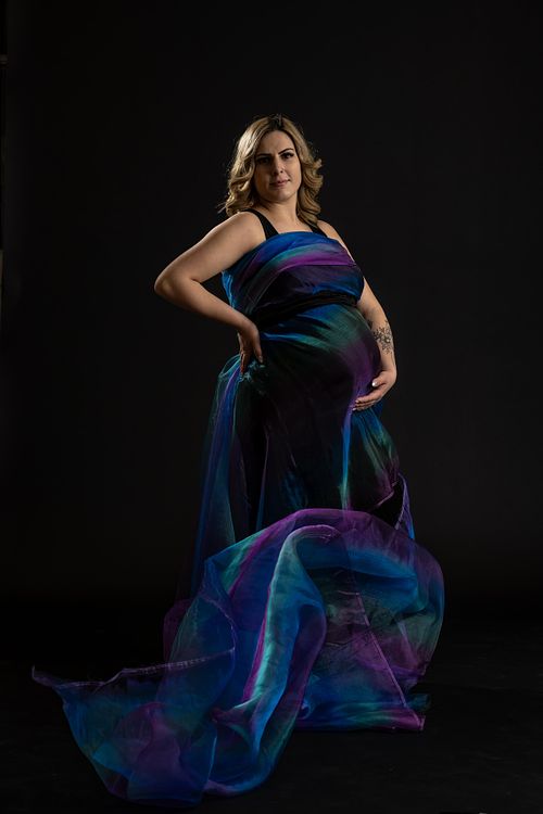 Creative portrait of expecting mother with rainbow fabric flowing around her.