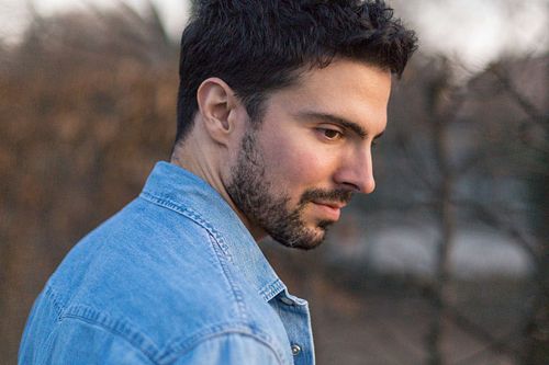 Headshot of Toni Gojanovic in a denim jacket standing in a park.