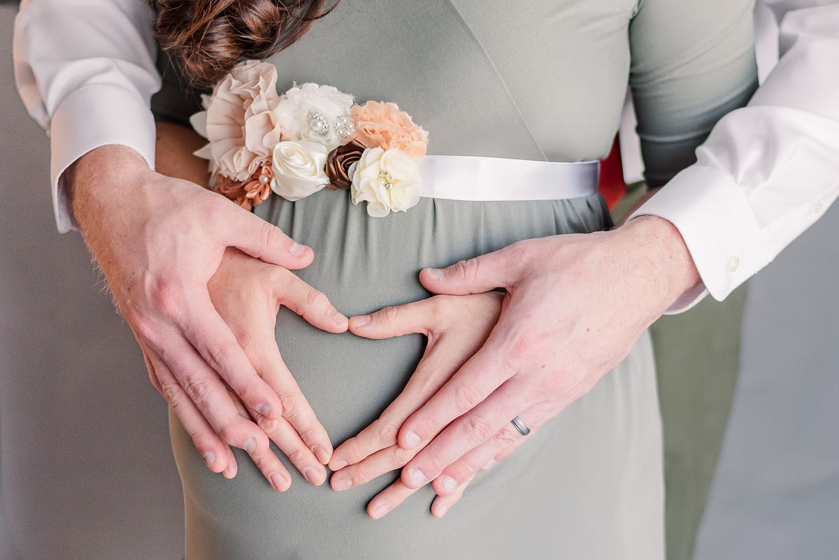 faceless, husband hugging pregnant wife from behind, their hands create heart-shape, session with Cranberry Township, PA photographer