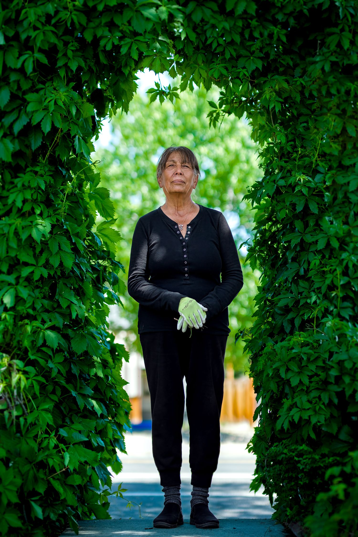 Environmental portrait of older woman standing in a garden archway