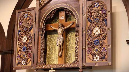 Detail showing the carving, painting, and fabric work on the Crucifix housing.