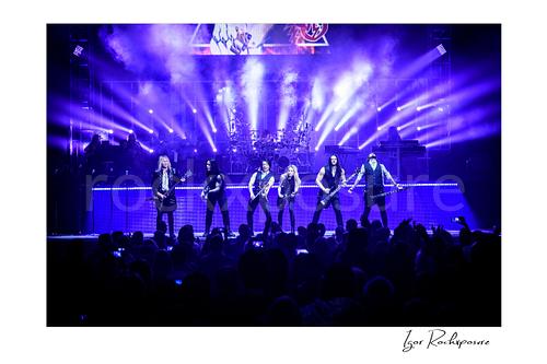 Horizontal color image of Trans Siberian Orchestra performing on stage with the full band under purple concert lighting