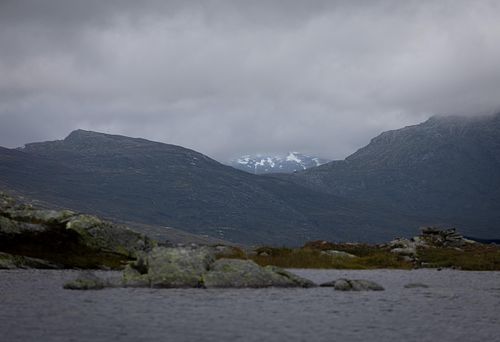 Photographie d’art de montagnes lointaines sous un ciel couvert.