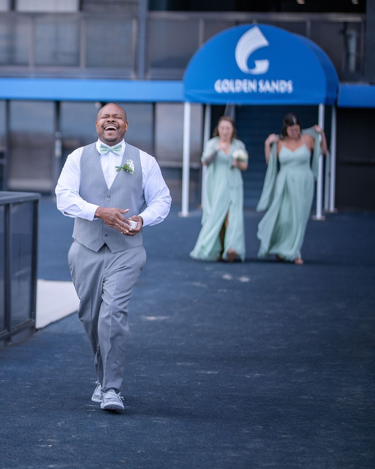 groomsman smiling and running towards groom in ocean city during an october beach wedding at golden sands