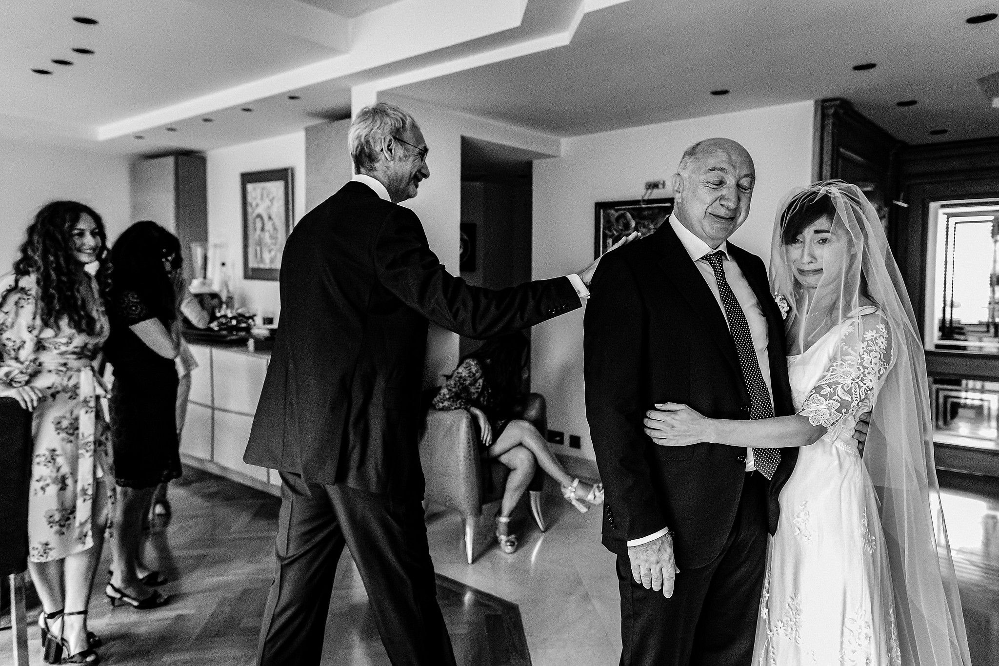 Oncle de la mari&eacute;e qui tape sur l'&eacute;paule de son fr&egrave;re. Le p&egrave;re de la mari&eacute;e et sa fille sont en pleurs captur&eacute; par S&eacute;bastien CLAVEL photographe de Mariage &agrave; Lyon et Gen&egrave;ve
