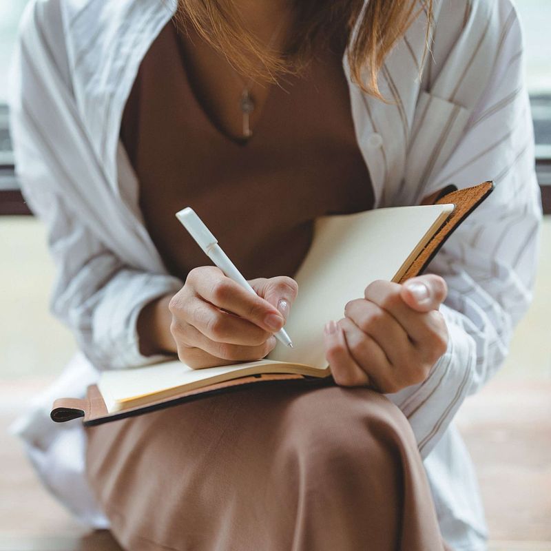 Woman writing in health journal or diary