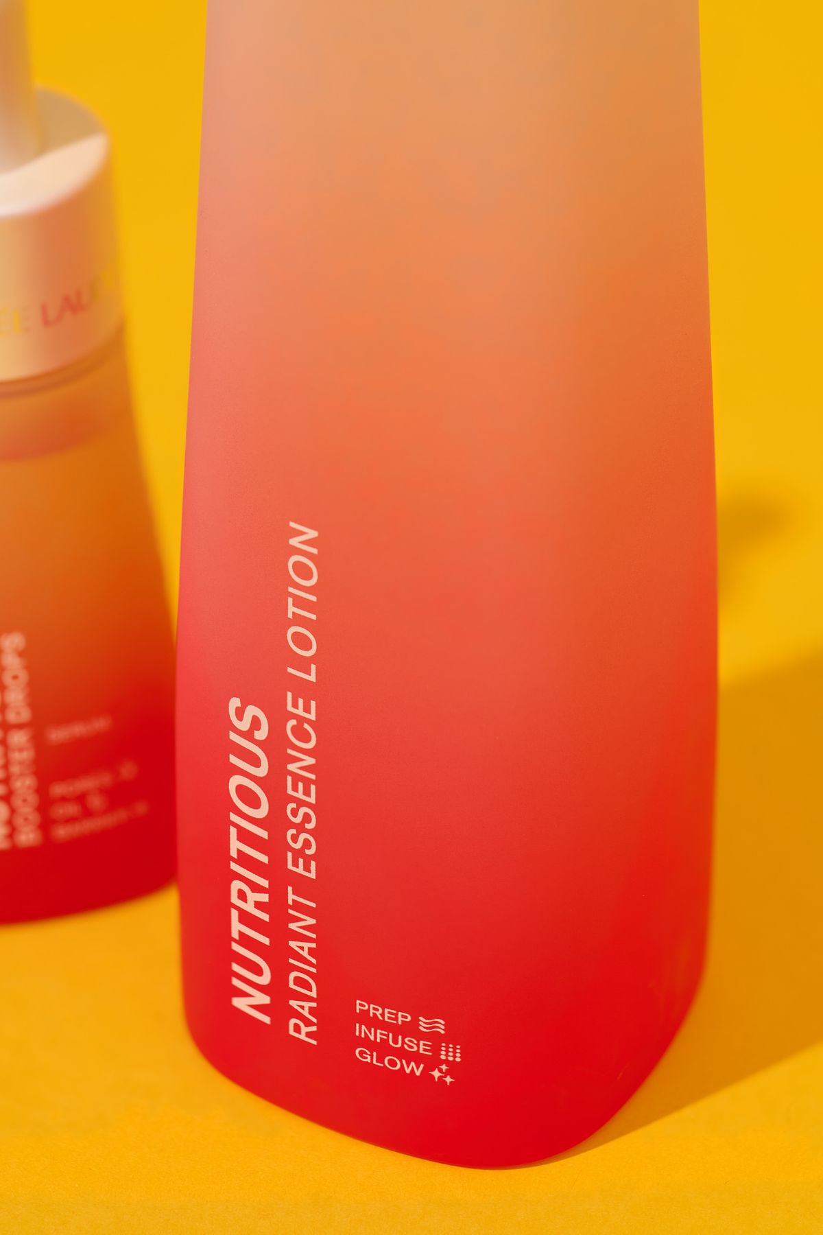 Close up of a red cosmetics bottle on a yellow background.