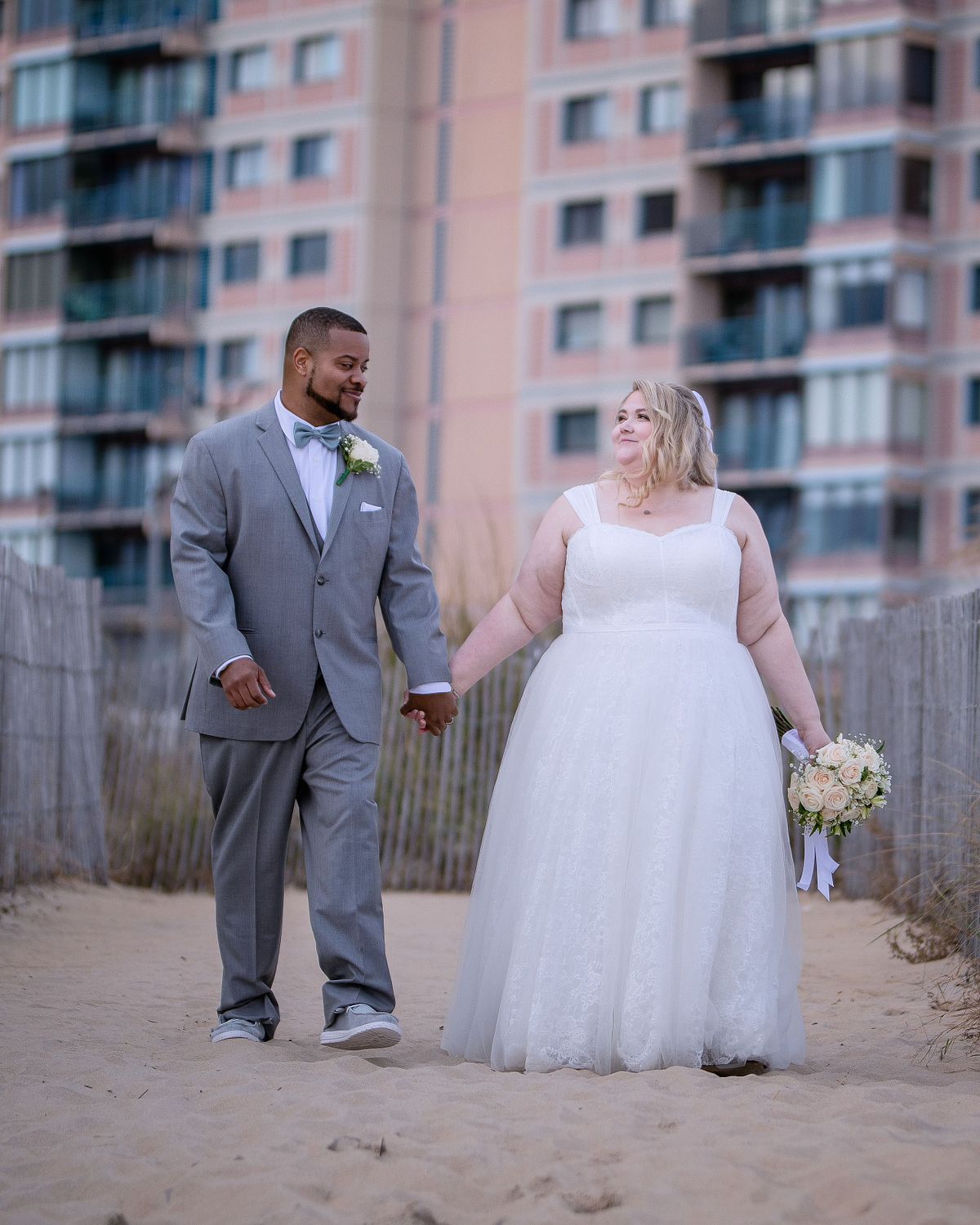 bride and groom walking towards an empty beach after the ceremony with bride holding the flowers during sunset hours in october