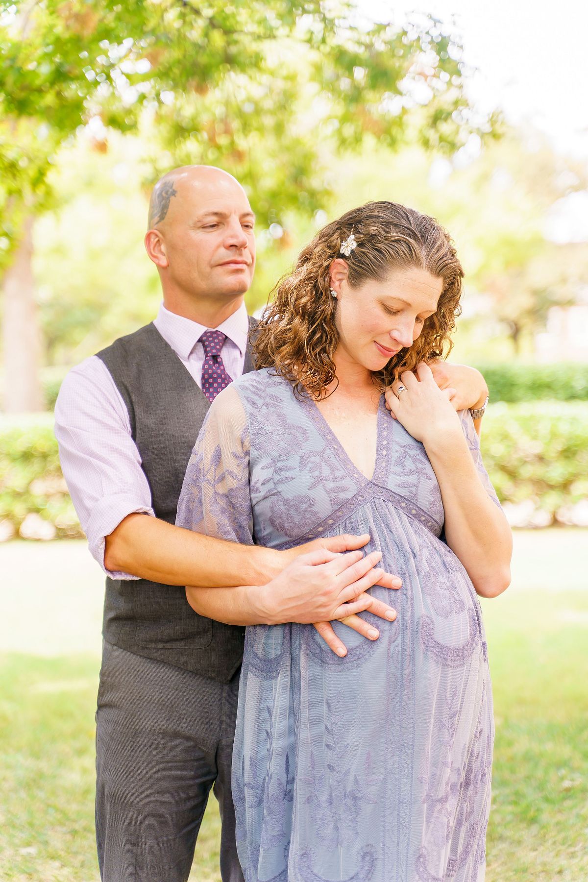 Pregnant woman posing in natural light with a flowing maternity gown.