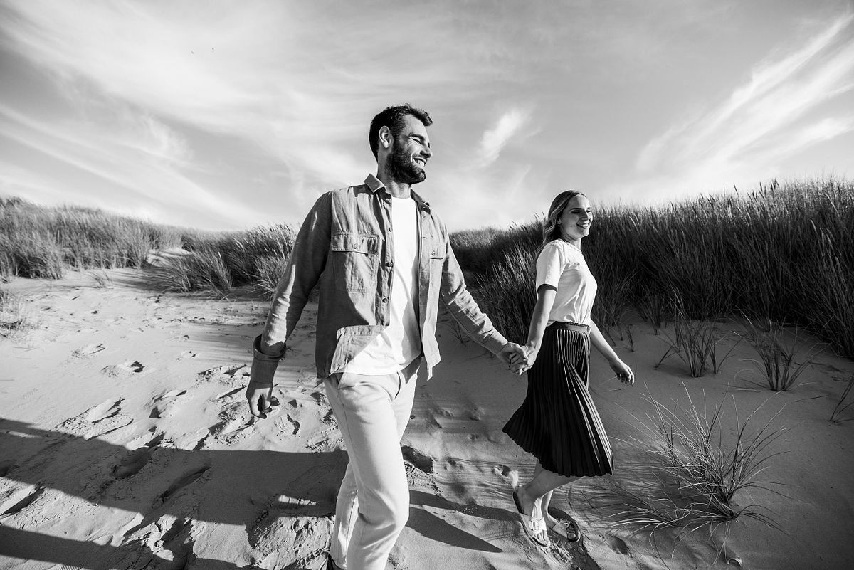 Zwart wit foto van het koppel die wandelt op het strand