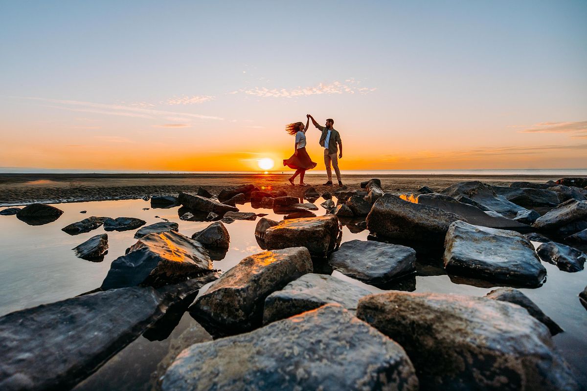 spontane fotografie - Koppel die danst tijdens golden hour aan zee