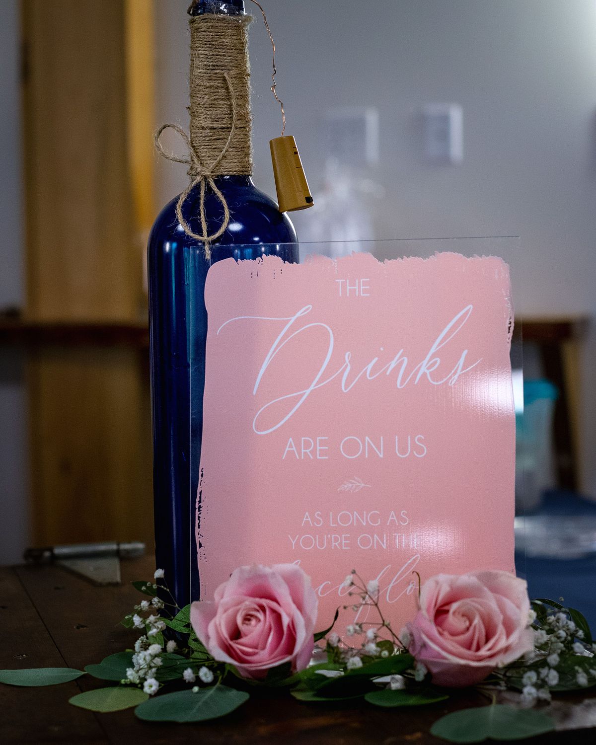 detail shot of a wine bottle, pink card and flowers on the table as decoration