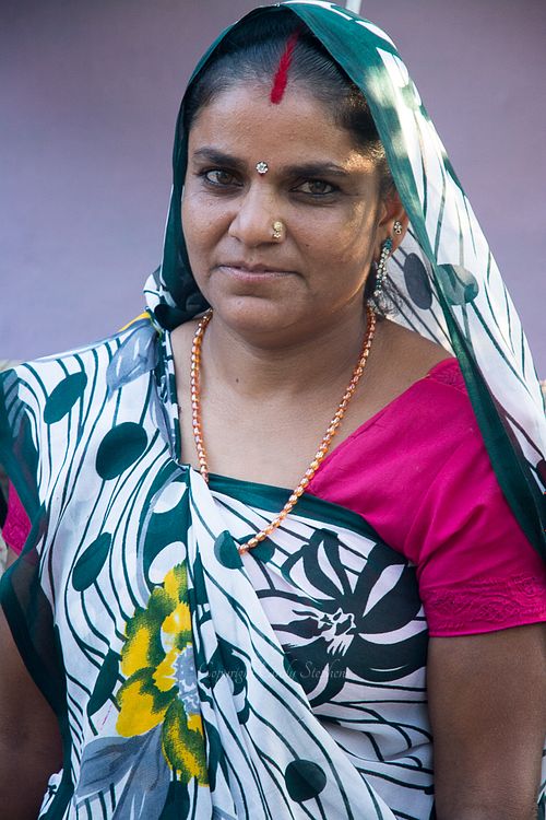 Sita Bhai Phoolchand Khushwaha, wearing a traditional sari and headdress, stands gracefully in Village Rancha, India, showcasing her cultural heritage.