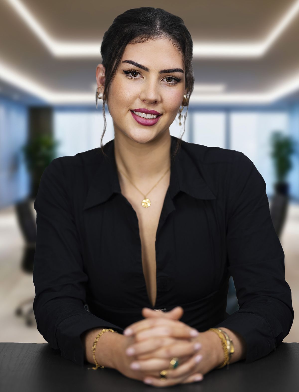 Corporate portrait of a young woman sitting at a desk in a a corporate boardroom..