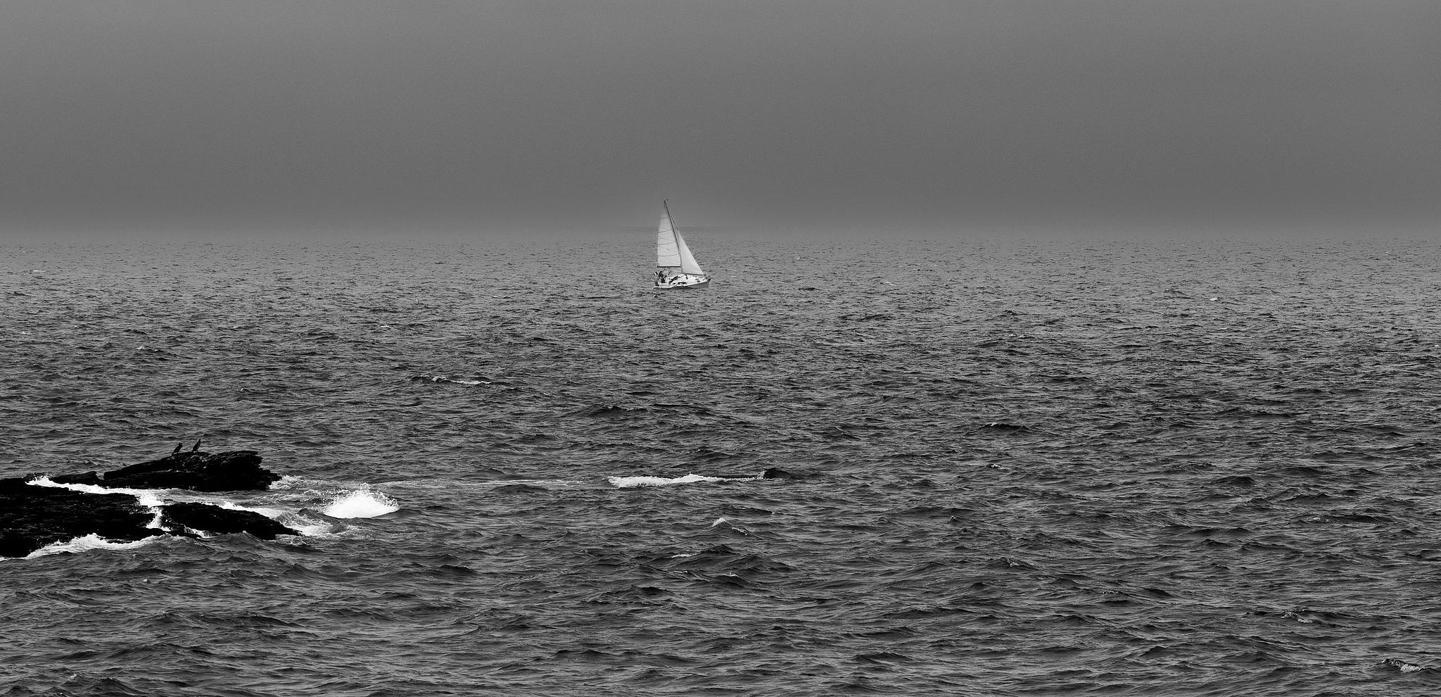 Voilier blanc sur mer sombre.