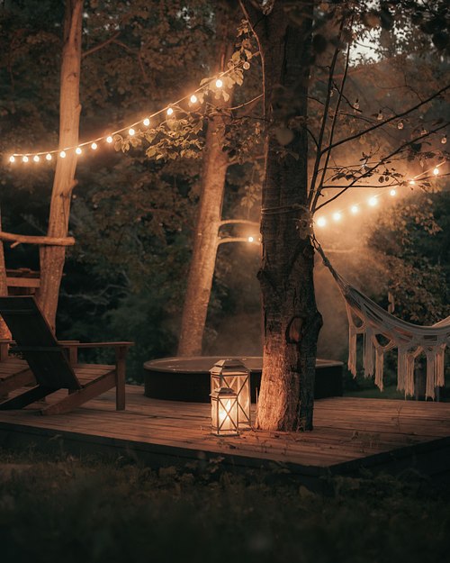 Evening lights outside a cozy black cabin in the forest