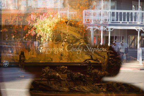 Cowboy hat reflection in foreground with a vibrant Jackson Hole Main Street scene in the background, capturing the essence of Western identity.
