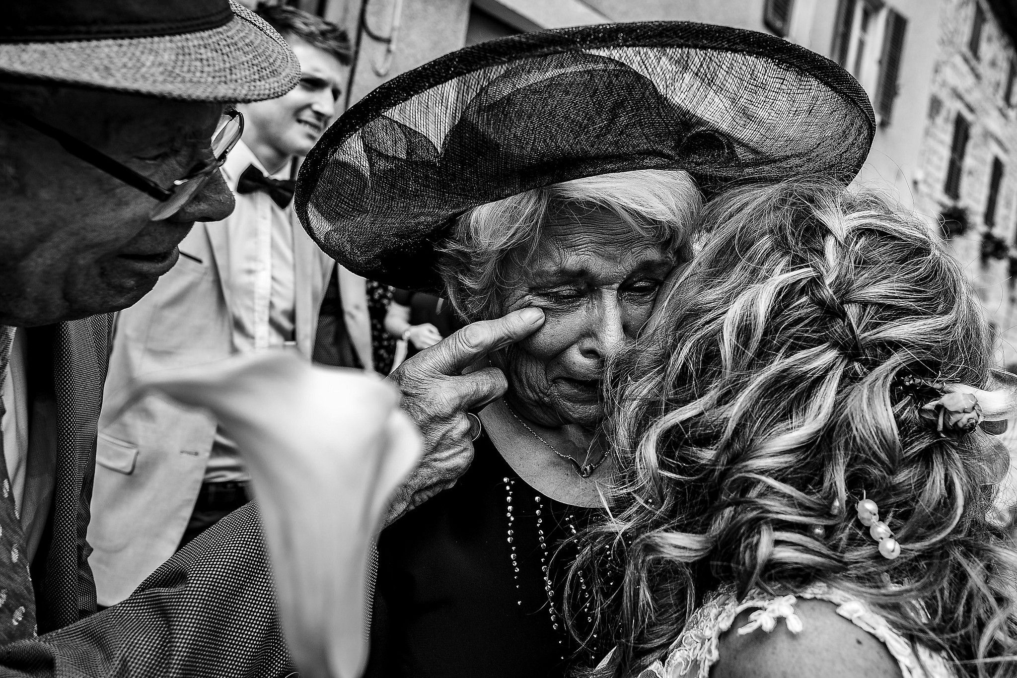 Mari&eacute;e qui embrasse sa maman. Son Papa essuie les larmes sur la joue de sa femme captur&eacute; par S&eacute;bastien CLAVEL photographe de Mariage &agrave; Lyon et Gen&egrave;ve