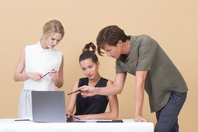 mężczyzna uczy kobietę, wskazując na szary laptop