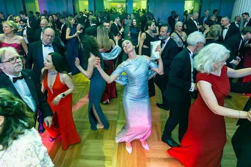 Crowd dancing in colorful gowns and tuxedos at Bundespresseball 2024 celebration.