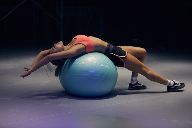 femme faisant du yoga sur un ballon de stabilité