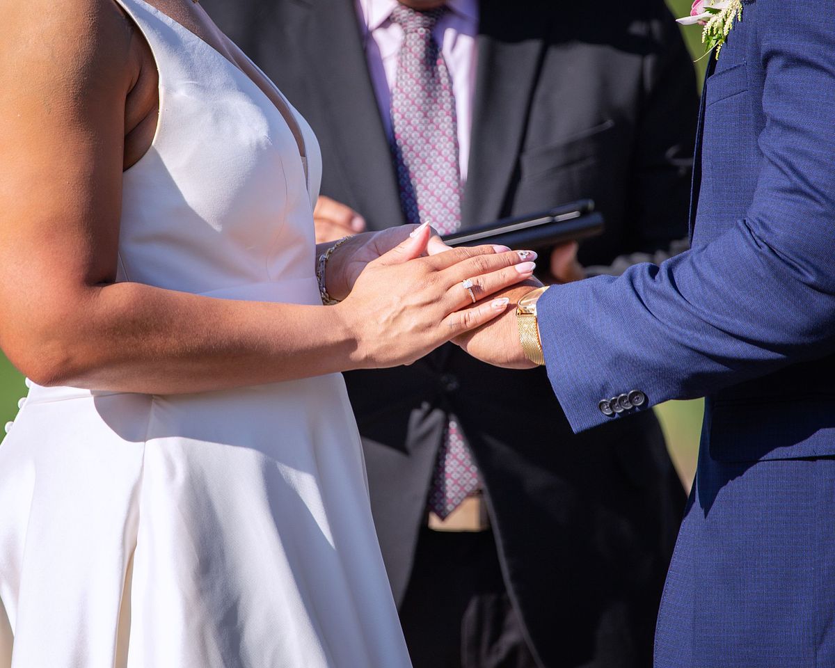 wife covering the hand of her groom during the ceremony after the ring exchange