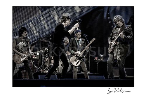 Horizontal black and white image of Ronnie Wood, Mick Jagger, Charlie Watts, Keith Richards and Mick Taylor of The Rolling Stones performing on stage together
