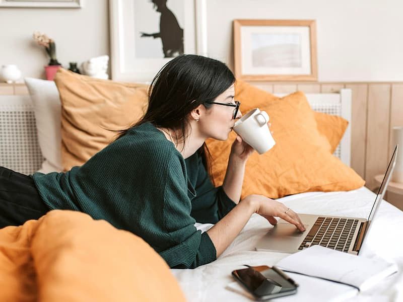 woman watching videos on laptop from bed