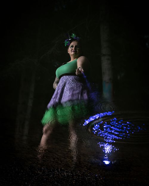 A powerful woman sprinkles magic into her reflection in the water.