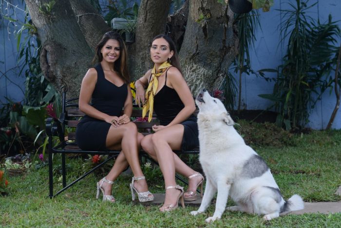 Models sitting on the chair for a photoshoot with a dog beside them