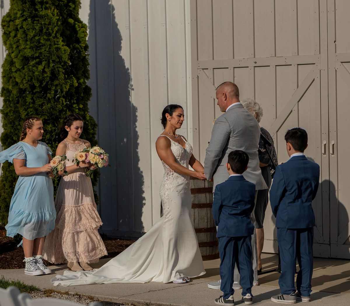 bride and groom holding hands during ceremony at kylan barn. they are surrounded by children