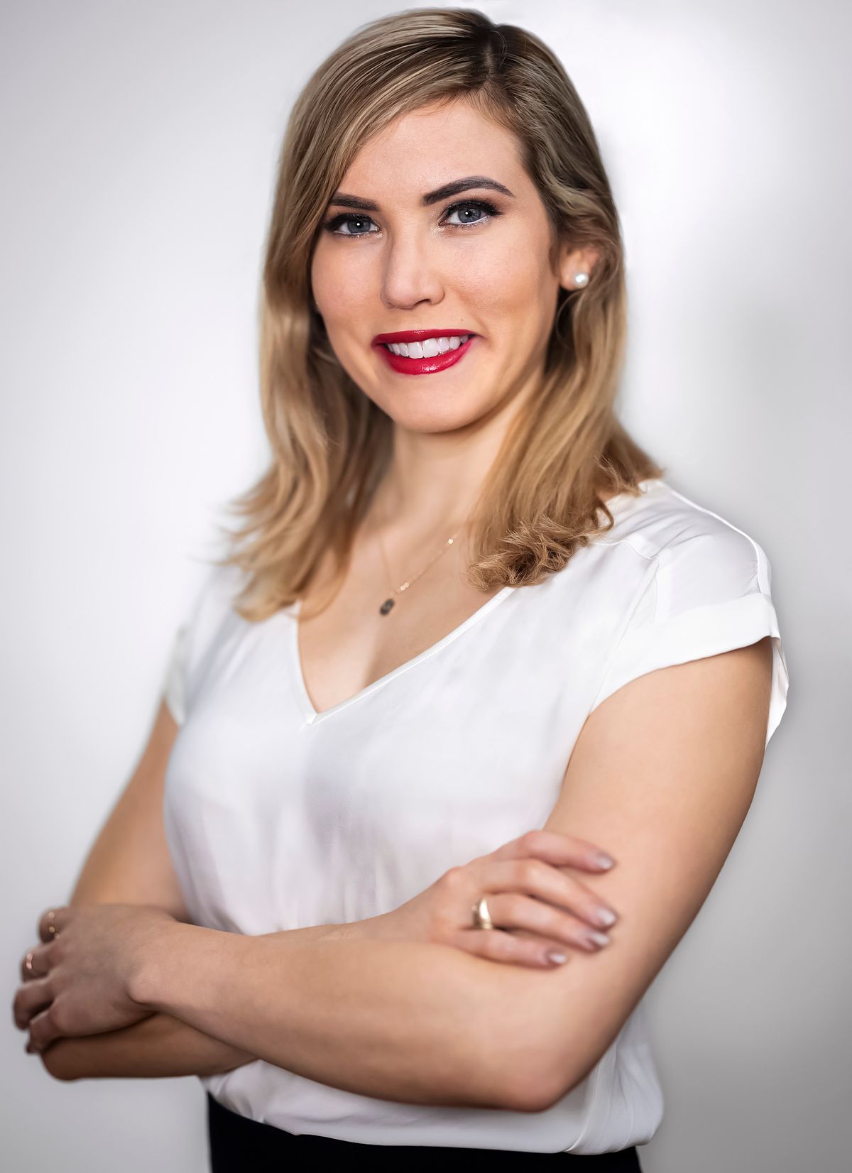 Corporate portrait of a young woman dressed in a white shirt taken on a white background.