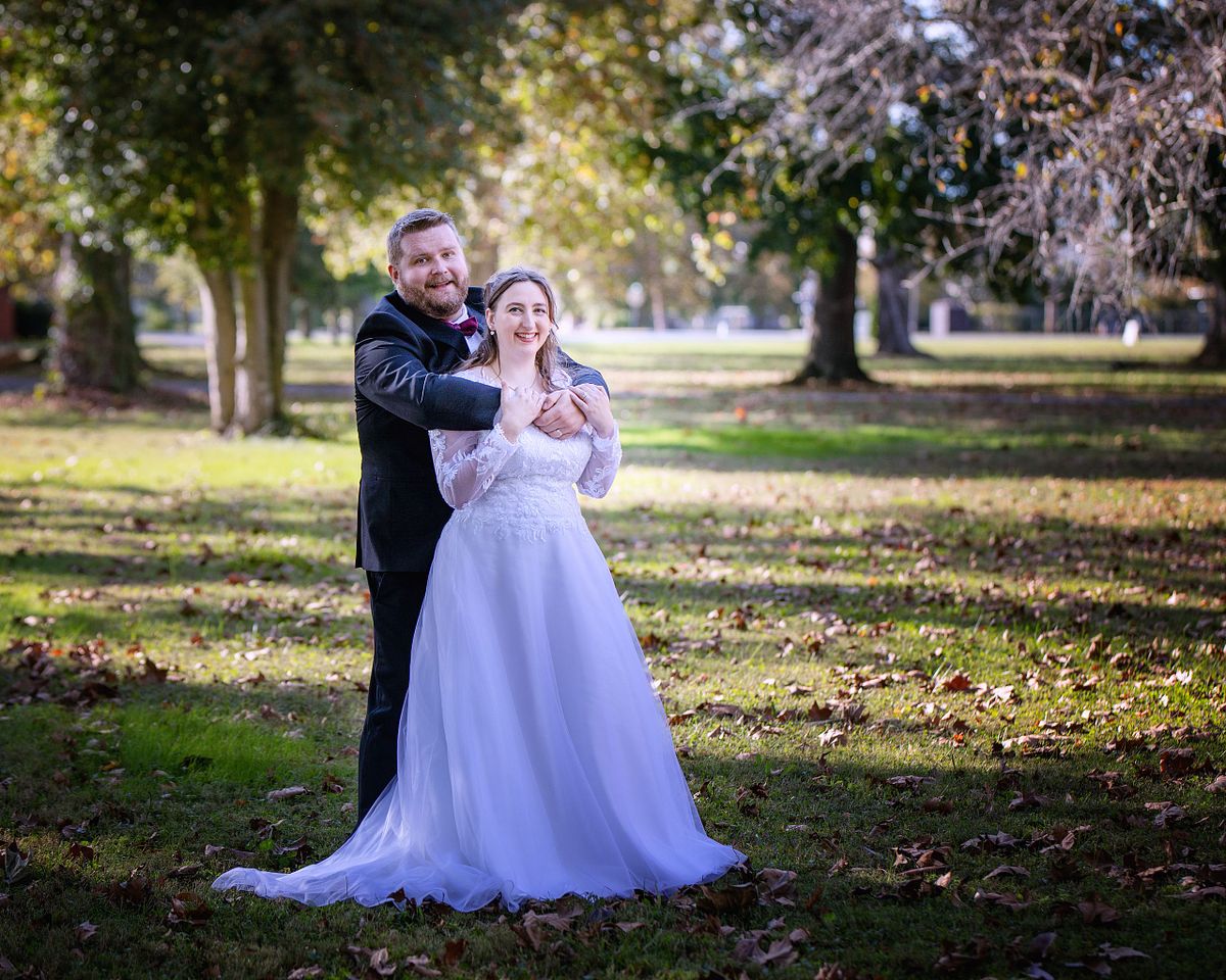 bride and groom posing underneath the ancient trees at ross mansion during golden hour