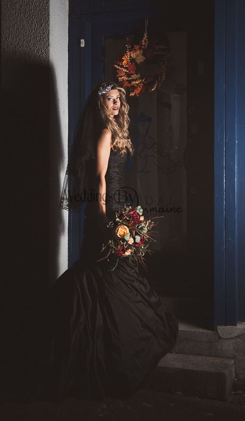 Model wearing a black wedding dress from Bridal Re-Loved Leicester, standing in a doorway, photographed by Weddings by Jermaine, with hair and makeup by Justaboutweddingshair and beauty, and accessories by Sydney Grace Bridal