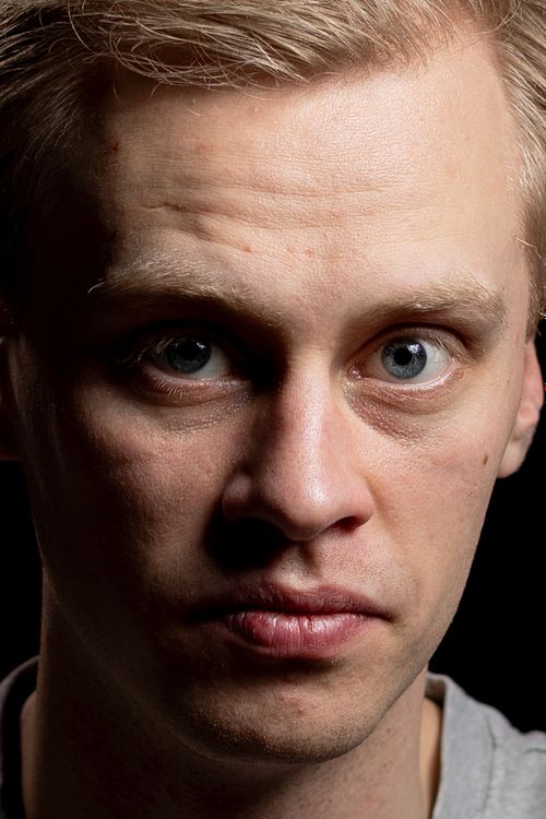 Närbild av blond man i riktat studioljus, intensiv blick