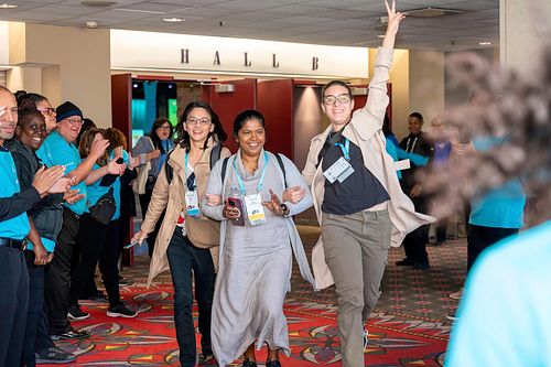 Attendees greeted with applause and excitement during high-energy tunnel welcome at Grace Hopper Celebration 2024 in Philadelphia, captured by professional event photographer.
