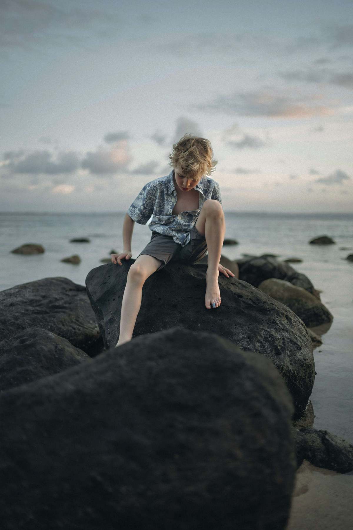 Boy climbing coastal rocks at dusk, natural unposed children's lifestyle photography UK