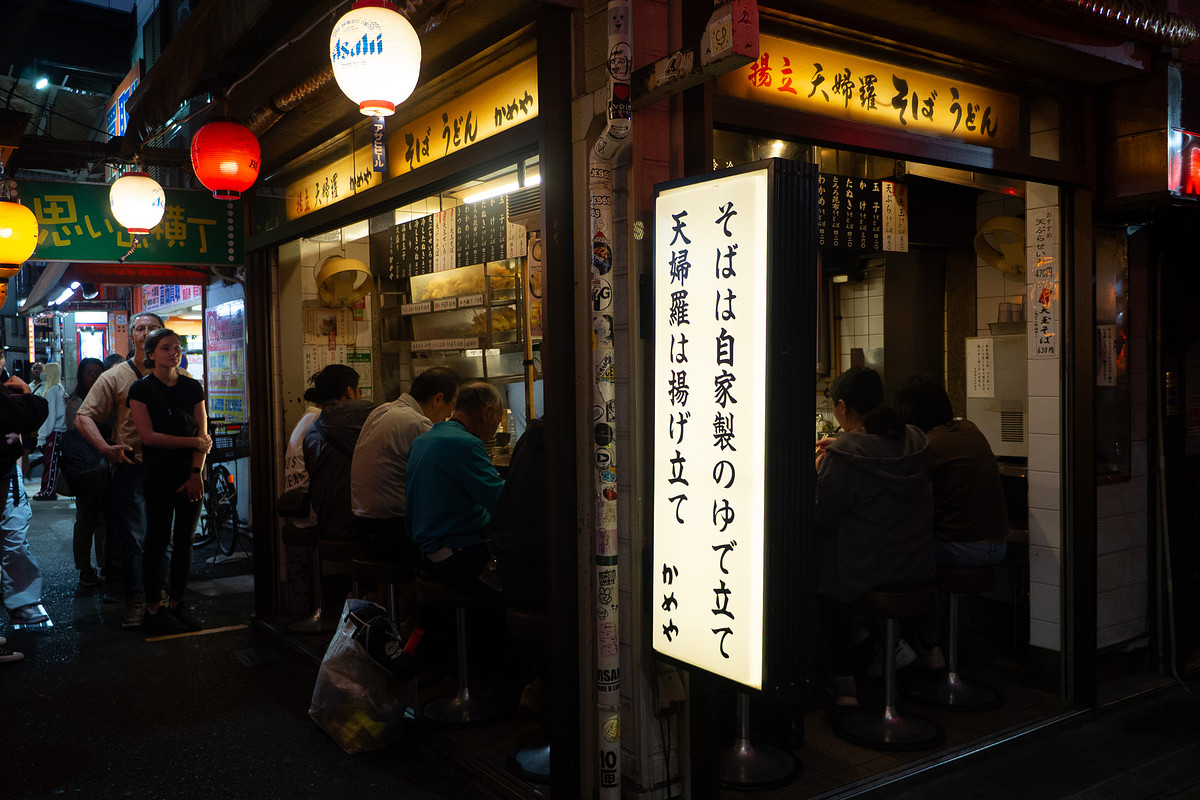 Stalle de soba debout à Omoide Yokocho, lanterne Asahi et clients au comptoir